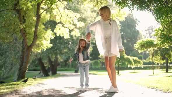 Carefree Happy Woman and Girl Dancing in Sunshine in Slow Motion in Spring Summer Park alt