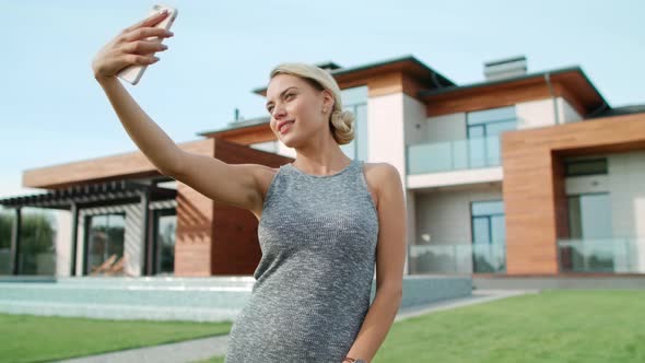 Smiling Woman Making Selfie Near Apartment. Closeup Blonde Woman Taking Photo alt
