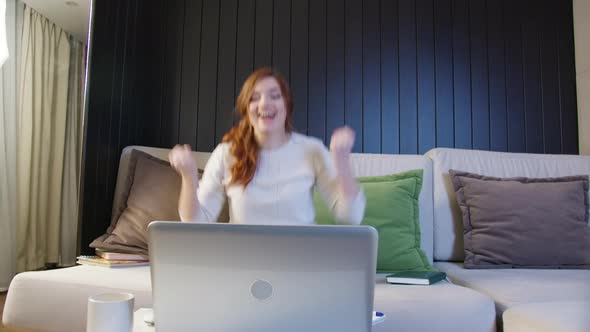 Excited Young Woman Winner Looks At laptop Celebrates Online Success Sits On Sofa At Home. alt