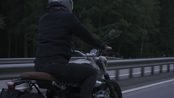 Man Riding Scrambler Motorbike on the Highway Through the Dark Forrest alt