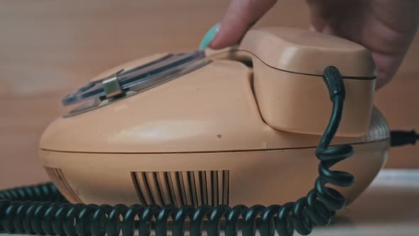 Woman's Hand Picks Up the Receiver of an Old Vintage Wired Telephone and Calls alt