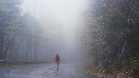 Carefree Confident Man Walking Along a Deserted Road in the Mist and Fog alt