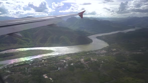 looking outside the airplane window when the plane is passing the mekong river in Laos alt