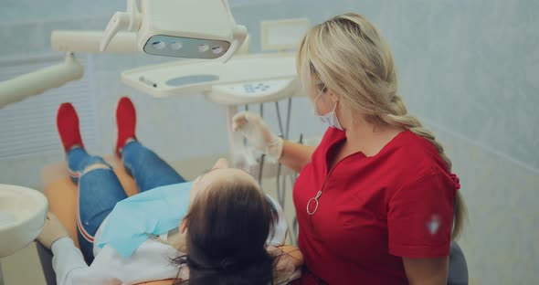 Handsome Dentist Directs the Lamp to the Patient and Lowers It Below Starts the Treatment of the alt