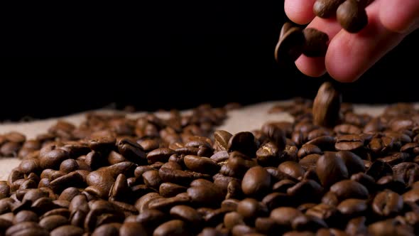 Hand mixing roasted coffee beans. Slow motion of arabica coffee seeds. alt