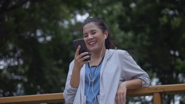 Smiling portrait beautiful young Asian woman fitness runner using mobile phone.