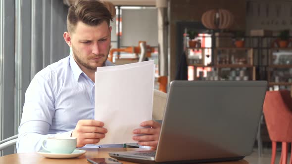Businessman Looking at Some Papers at the Cafe alt
