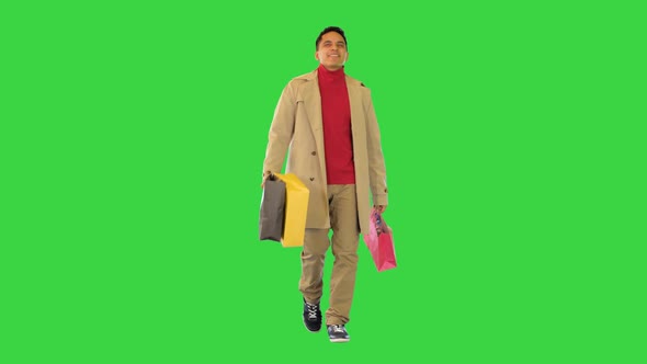Joyful Trendy Man Return From Shopping Carry Bags with Fashion Clothes Stylish Latin Guy in Trench