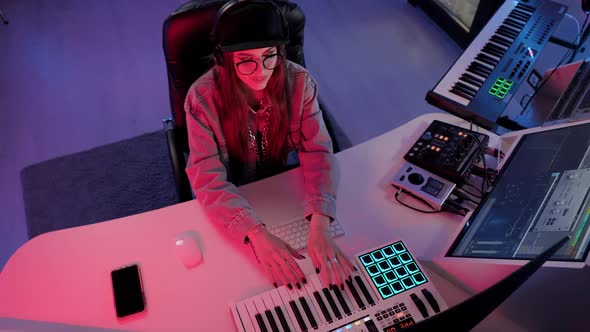 Woman Musician in Cap and Headphones Working in the Recording Studio with Computer and Mixer