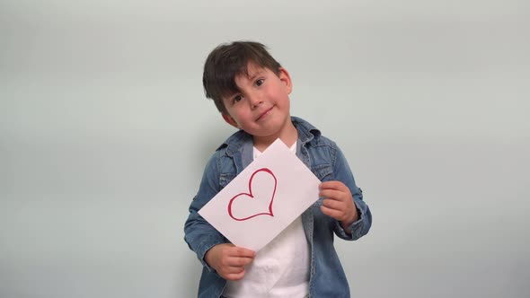 A Boy Holds a Piece of Paper with a Drawn Heart and Laughs A Cheerful Child Shows a Sign with a alt