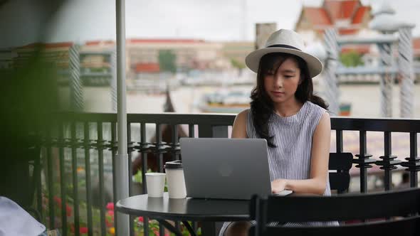 Young Asian woman using laptop working at a cafe in Thailand.