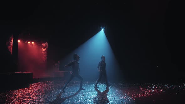 Two men in a costume dances under beautiful lighting in the circus arena.