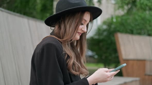 A Young Woman Scrolls the Page on a Smartphone