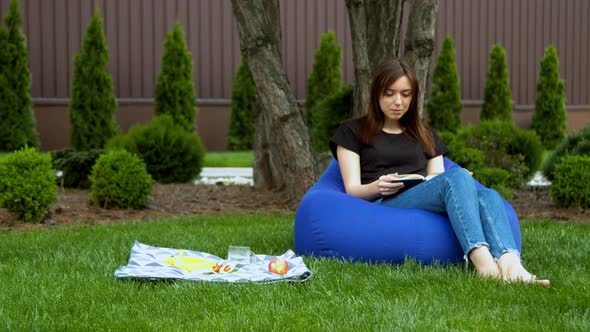 Young Woman Reading Book in Garden