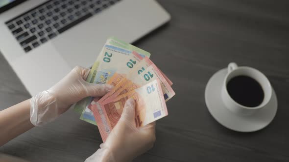 Woman in Protective Gloves Counting Euro Banknotes Money on the Table in Cafe and Working alt