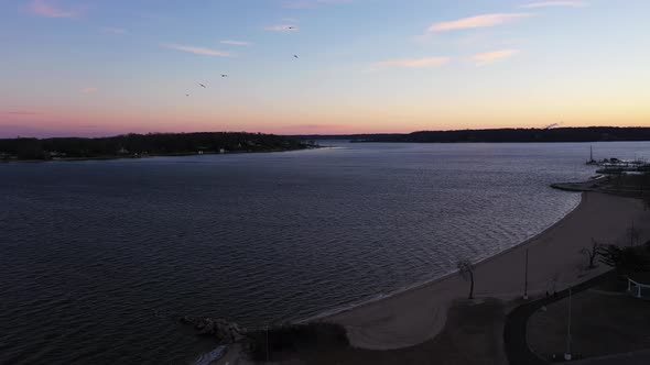 an aerial shot over an empty park looking at the bay during a beautiful sunrise. The sky is pink and alt