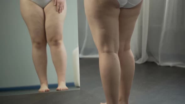 Girl Examining in Mirror Her Sagging Cellulite Body, Pondering About Surgery alt
