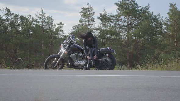 The Young Woman Changing Her Shoes Sitting on Her Bike on the Road alt