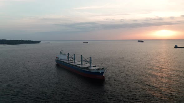 A drone flight around container ships into the sea at sunrise alt