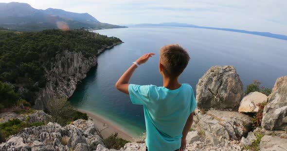 Young 10s-11s Years Traveller with Arms Raised on Top of Mountain Looking at View of Adriatic Sea alt