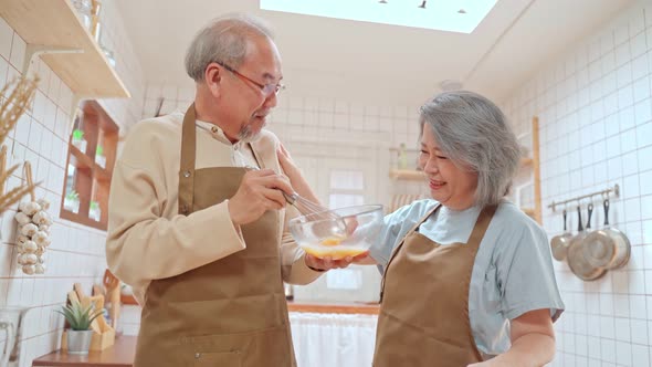 Asian senior older couple spend time together, husband stirring eggs, wife laughing with joke story. alt