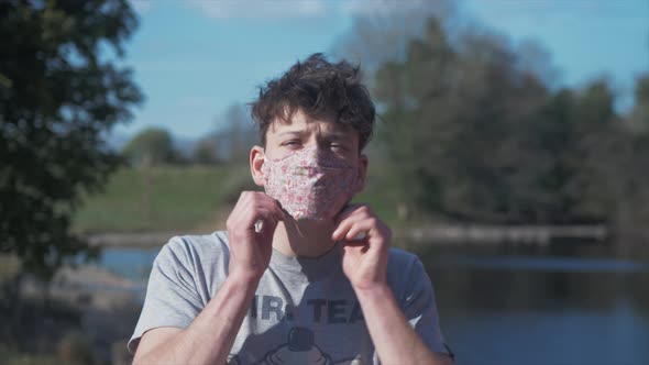 Young man puts on homemade flower pattern corona virus cotton mask MEDIUM SHOT alt