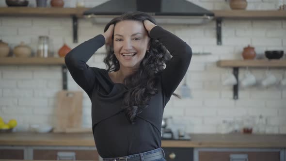 Middle Shot Portrait of Young Cheerful Caucasian Woman Winking and Smiling Holding Hands on Head alt