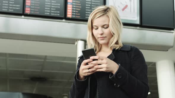 Young Adult Female looking on smart phone and waiting in airport