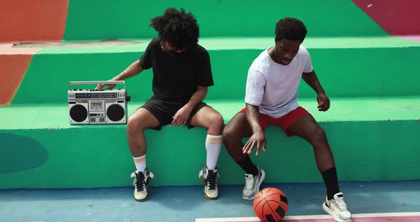 Young african people listening music from vintage boombox stereo outdoor after basketball match alt