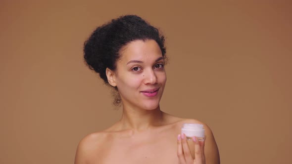 Beauty Portrait of Young African American Woman Smears Face Care Cream on Tip of Her Nose and Smiles alt