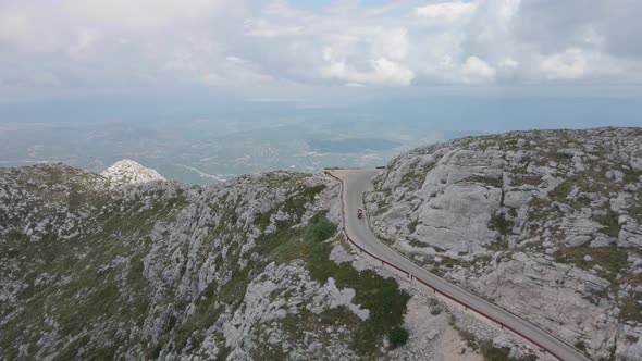 Two People on a Scooter Climb the Winding Alpine Road to the Highest Point in Biokovo in Croatia
