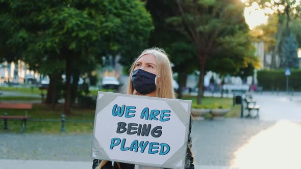 Pretty Girl Wearing Medical Mask Protesting Against Authorities That Playing Human Lives alt