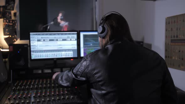 Music Producer in Headphones Working on Soundboard alt