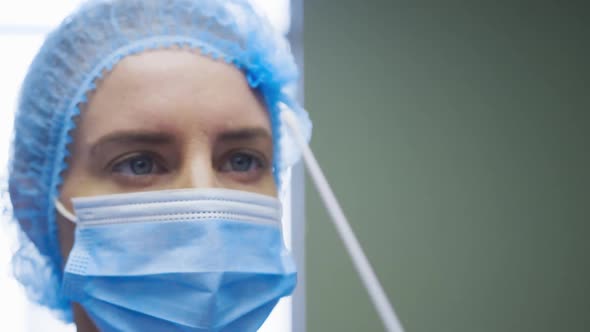 Female caucasian doctor wearing protective clothes reparing covid swab test for patient alt
