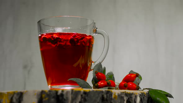 Tincture Of Herbs And Red Berries In A Cup, Tea From Medicinal Rose Hips On A Wooden Background alt