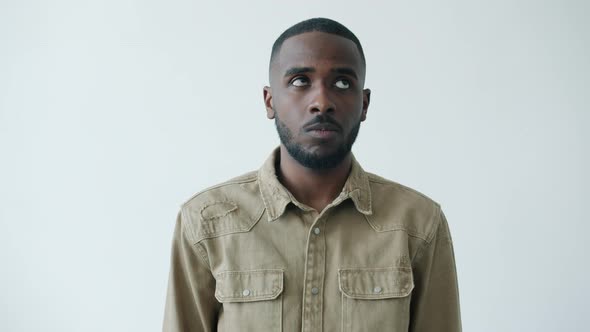 Confused African American Man Rolling Eyes Looking Around Then Looking at Camera on White Background alt
