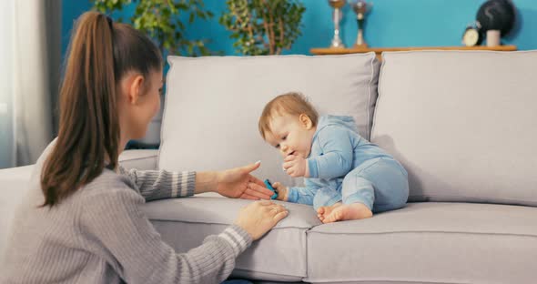 A Sweet Cute Handsome Little Boy Dressed in a Blue Bodysuit Twists Across the Couch alt
