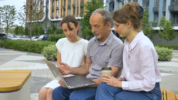 Senior Businessman Mentor or Coach is Teaching an Interns Pointing at Laptop Screen Helping New alt