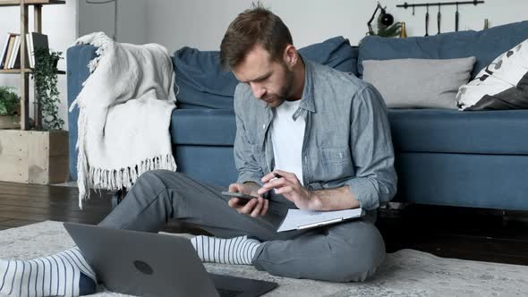 Young Man Sitting in Living Room Using Laptop at Home, Prints A Message, A Freelancer Works