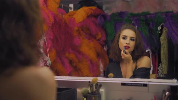 Actress Beautiful Girl Paints Lips with Red Lipstick in Front of a Mirror in a Dressing Room Makeup
