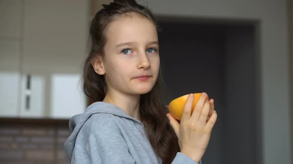 Little Girl with Long Hair is Licking a Half of the Orange alt
