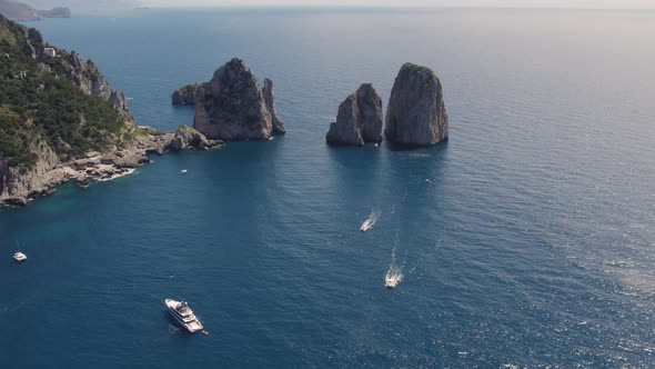 Iconic sea stacks (Faraglioni) off Capri coast, Bay of Naples, Italy; drone alt