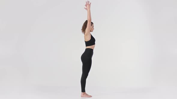 Young Lady Wearing Black Suit Demonstration Utkatasana Yoga Pose Raising Hand and Doing Squat Full alt
