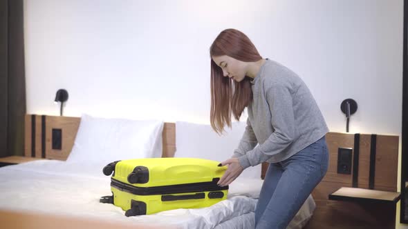 Beautiful Teenage Girl Closing Yellow Travel Bag. Portrait of Confident Caucasian Teenager Packing alt