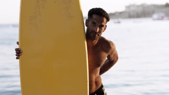 Portrait of Young Professional Black Surfer Man Holds His Surfboard in Arm Stands on Ocean Beach alt