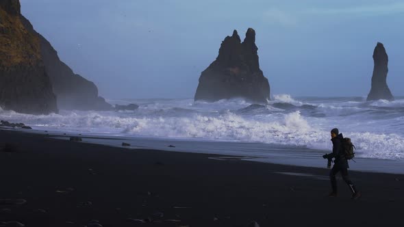 Photographer Running Along Black Sand Beach Towards Rough Sea alt