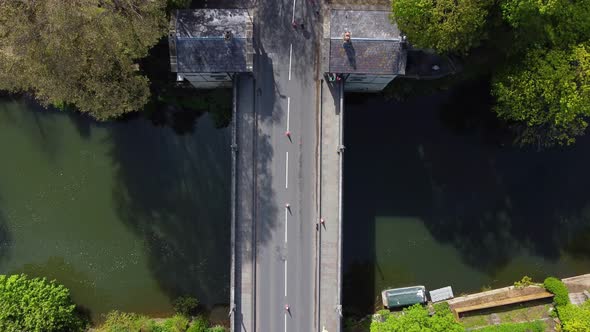 Top down aerial of a road bridge with traffic cones in the middle of the road, toll houses on edge alt