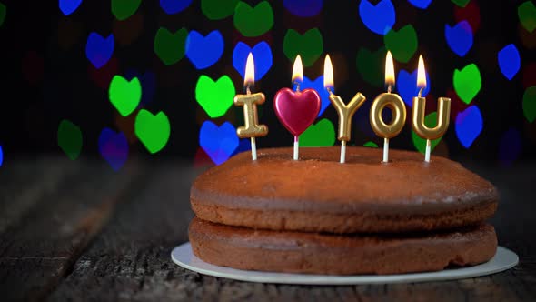 Pan Shot of Simple Valentines Day Cake with Lit i Love you Candles with a Colorful Background