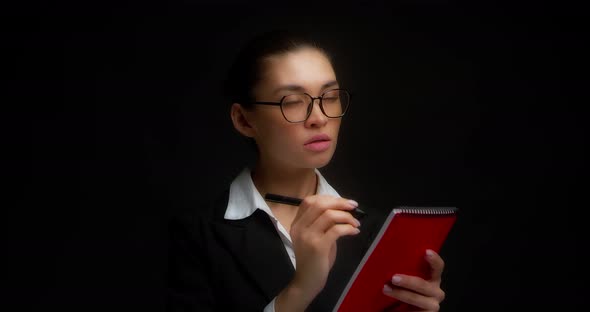 Thoughtful Business Woman Thinks What to Write in a Red Notebook