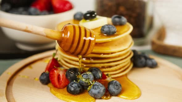 Pouring Honey or Maple Syrup on Pancakes with Berries on Top Closeup alt